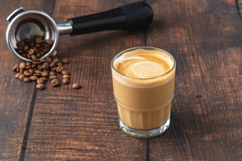 Cortado coffee with coffee beans next to it