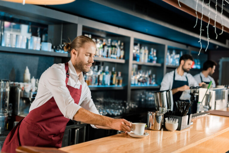 barista in apron with a cup of coffee