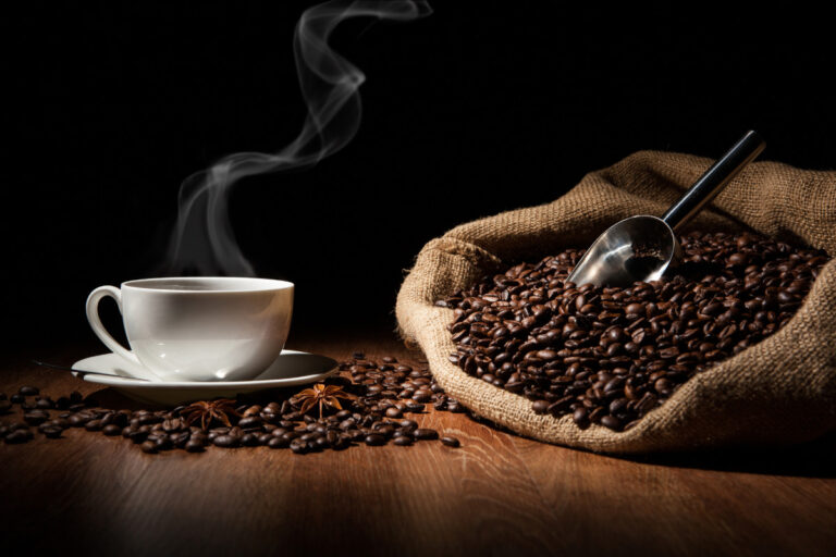 The Best Movies About Coffee coffee in white cup next to coffee beans in a burlap sack