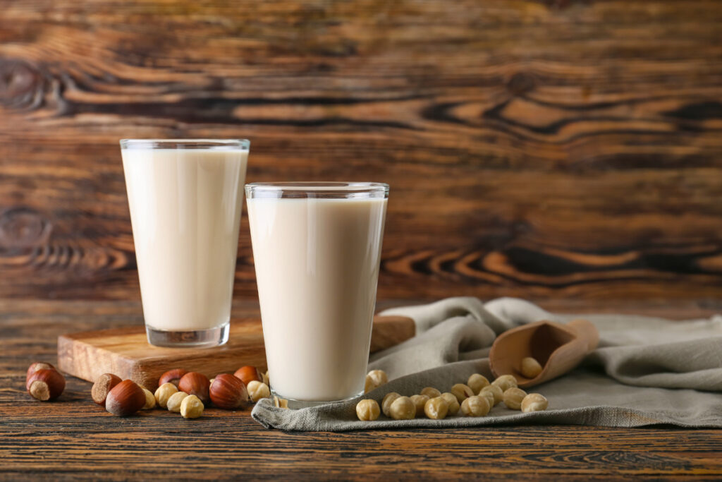 Glasses of hazelnut milk on dark wooden background