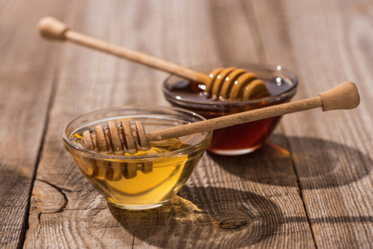 Honey: The Definition and Meaning Jars with honey and honey dippers on wooden table in sunlight