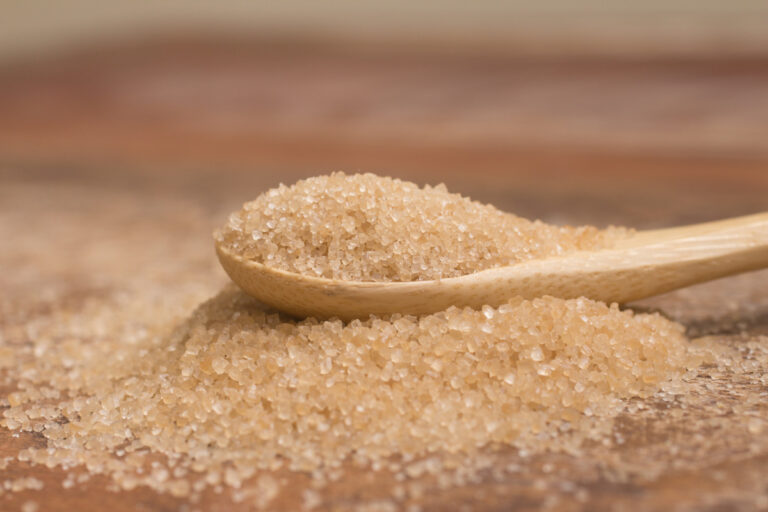 Pile of demerara sugar in a spoon over a wooden table