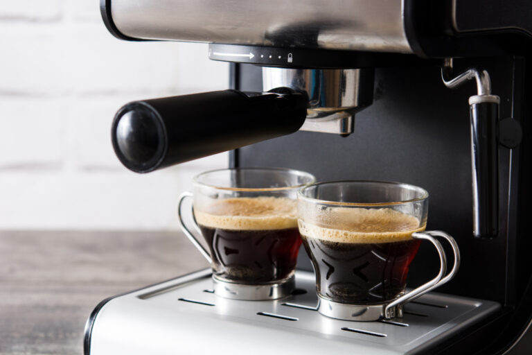 fresh coffee with crema in espresso machine on wooden table