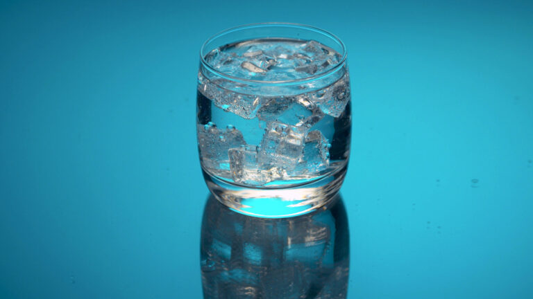 tonic water in a glass with ice cubes on a blue background