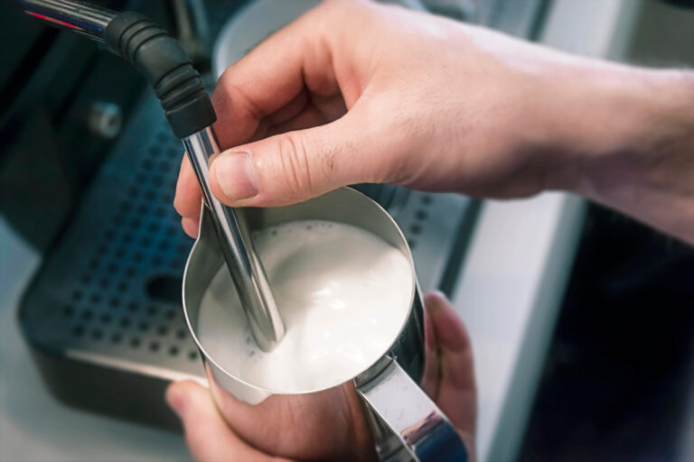 Barista steaming milk with a steam wand in a coffee shop