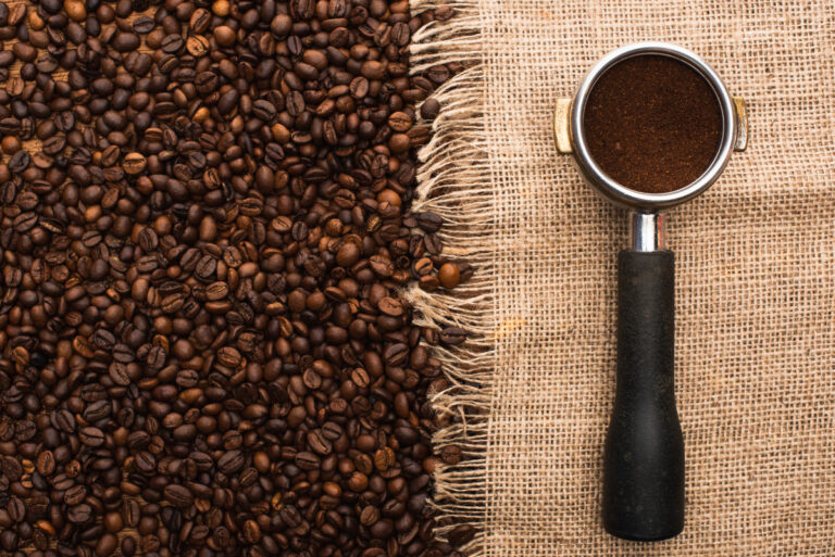 Top view of fresh roasted coffee beans and filter holder with ground coffee