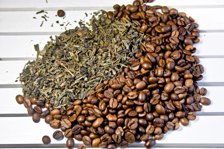 coffee beans and green tea leaves on a white wooden table