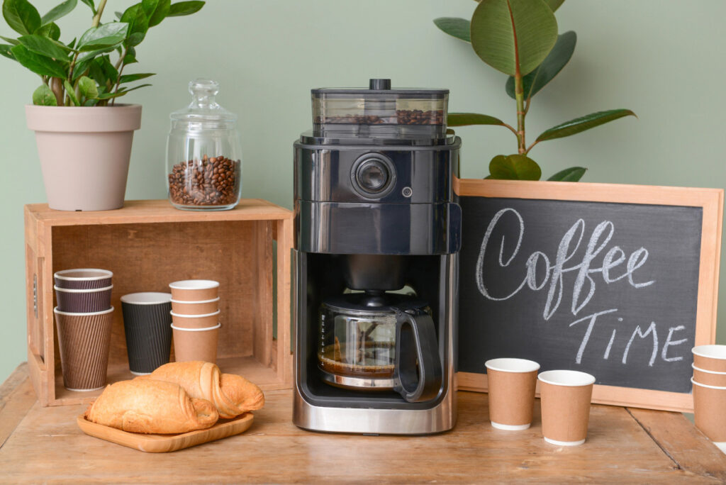 drip coffee maker, cups and croissants on kitchen table