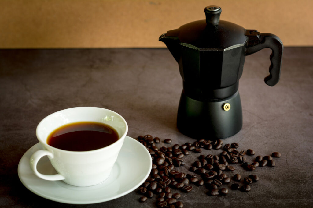 moka pot with coffee beans on dark table